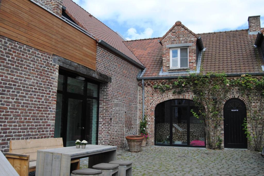 a patio with a table and chairs in front of a brick building at De Sjeiven Dorpel in Maaseik