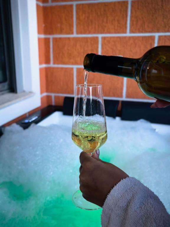 a person pouring wine into a wine glass at Jacuzzi Central Apartment in Shkodër