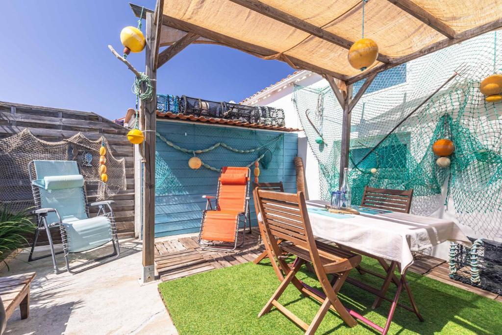 a patio with a table and chairs under an umbrella at Petite Maison Typique in La Cotinière