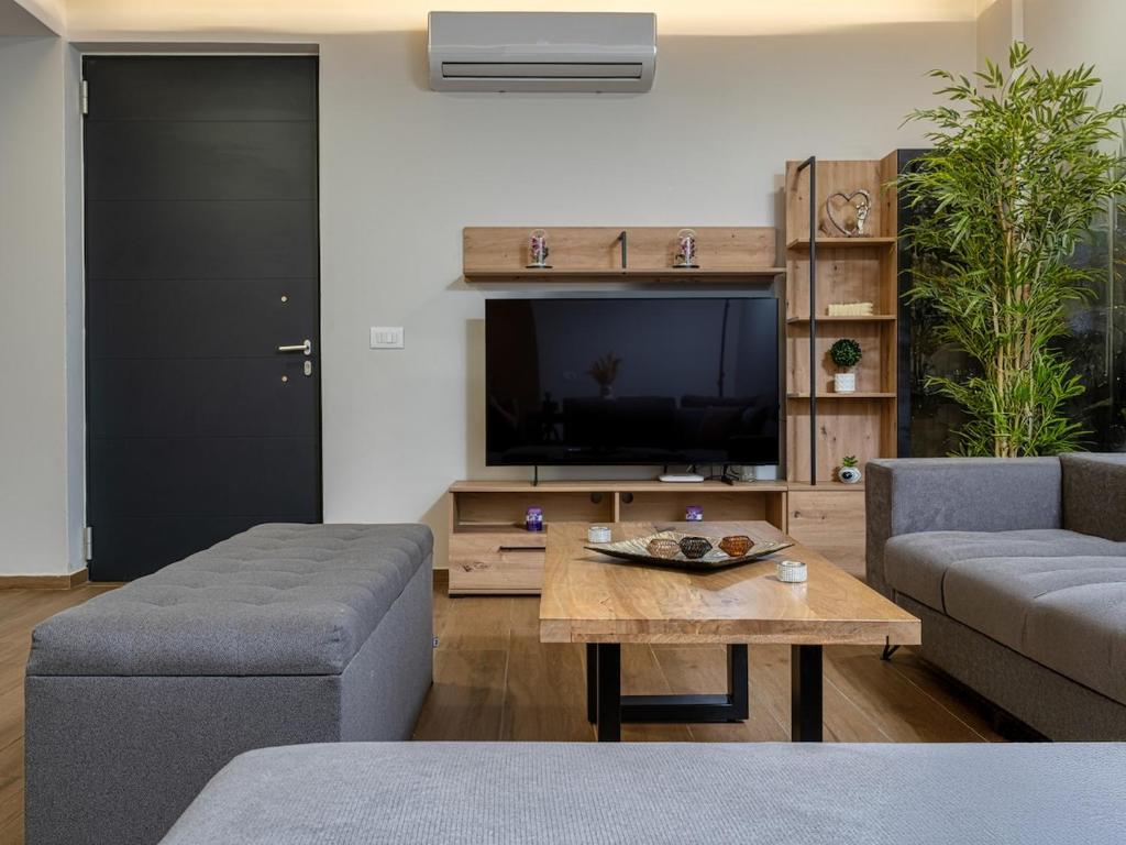 a living room with a couch and a table and a tv at Jasemina Luxury Apartment in Agios Nikolaos