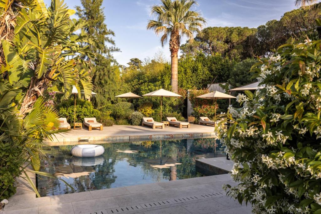 a pool with chairs and umbrellas in a garden at La Bastide des Salins in Saint-Tropez