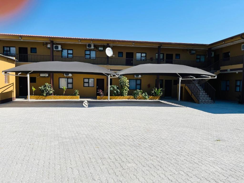 a building with a large parking lot in front of it at Otam-Check Guest House in Ondangwa