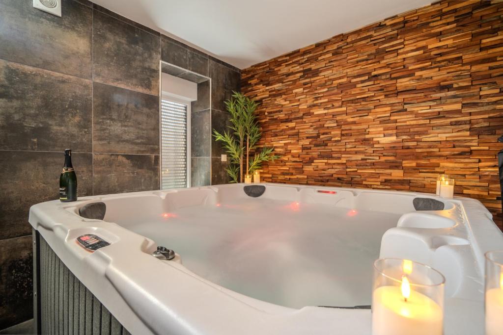 a white bath tub with candles and a bottle of wine at EnergyZen - Spa Alsace - le Refuge des Anges in Bischoffsheim