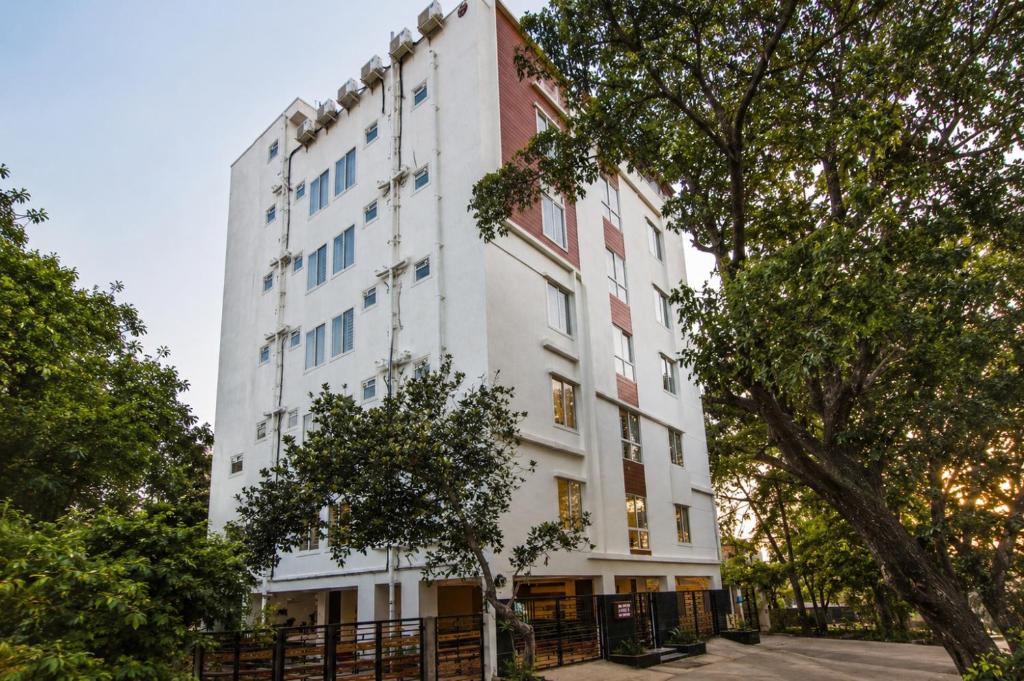 a white building with trees in front of it at Sanctum Suites Whitefield Bangalore in Bangalore