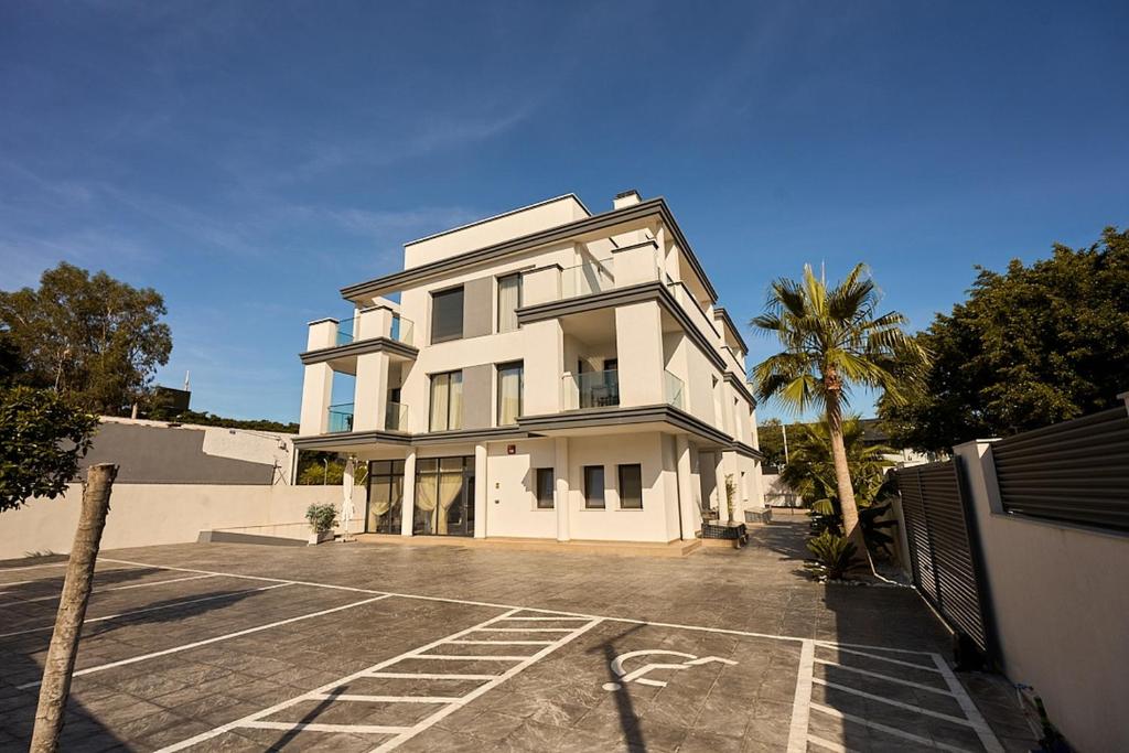 a white house with a palm tree in a parking lot at Magnolia in Alicante