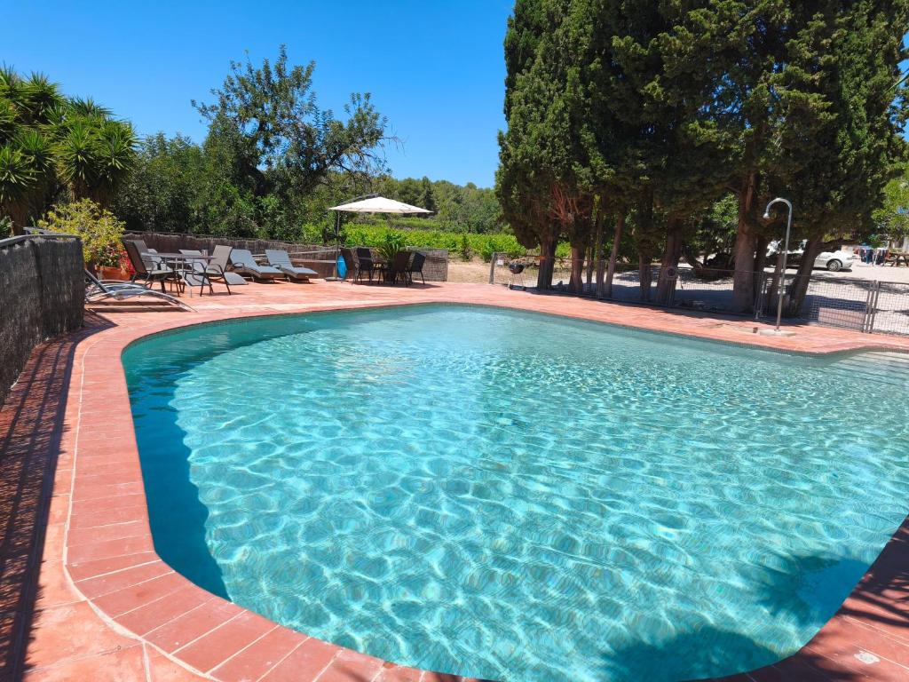 a large blue swimming pool with tables and chairs at Apartamento II Els Cucons in Sant Pere de Ribes