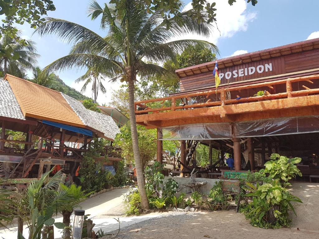 un restaurante con una palmera frente a un edificio en Poseidon Resort, en Ko Tao