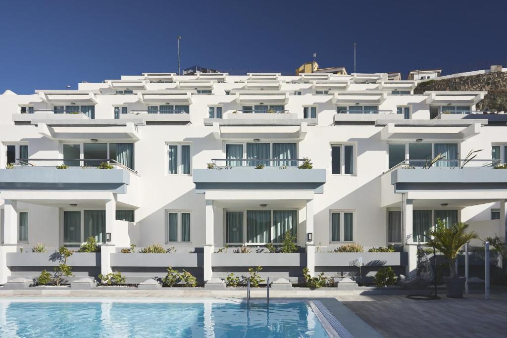 a white building with a swimming pool in front of it at Mariposa del Sol in Patalavaca