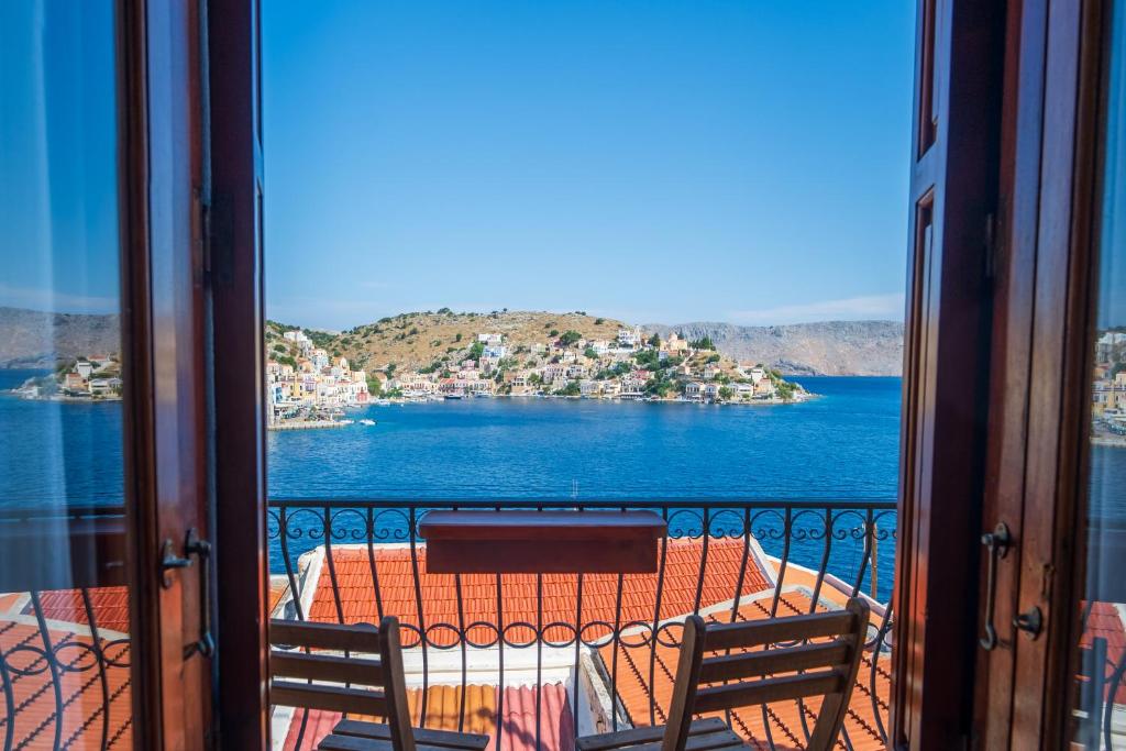 a balcony with a table and chairs and a view of the water at Villa Pitini in Symi