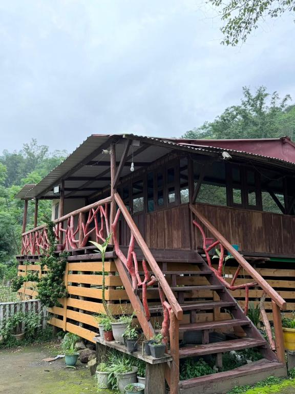 a wooden building with a staircase leading up to it at The Hojai Farmland in Hāflong