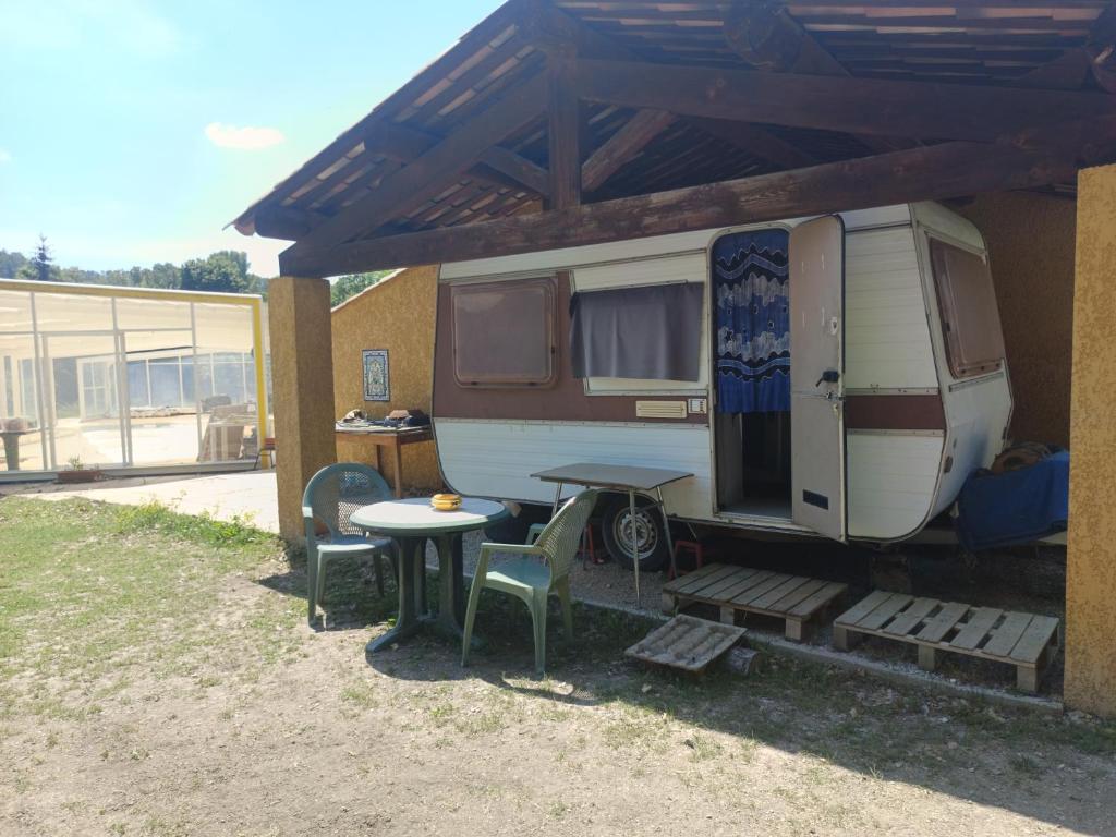 a rv parked under awning with a table and a picnic table at Divine Caravane in Digne-les-Bains