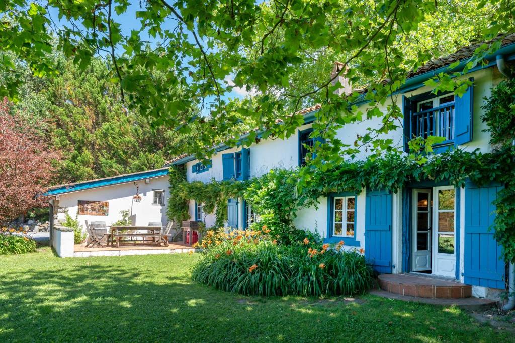 a house with blue shutters and a yard at Maison De Charme Avec Jacuzzi in Arcangues