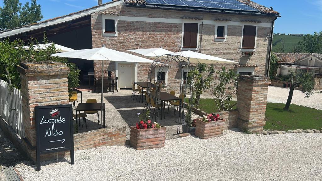 a patio with tables and umbrellas in front of a building at Locanda il nido in Moscolo