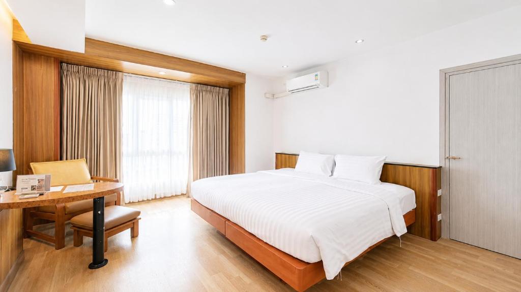 A bright room with a large bed, window, and built-in desk area.