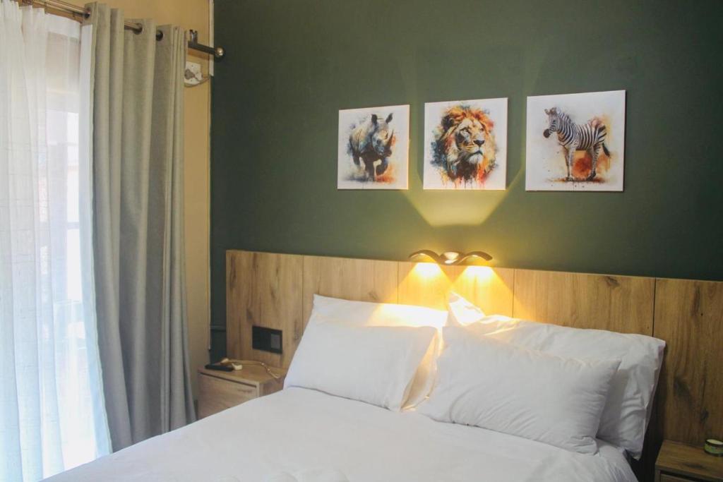 a bedroom with a bed with four pictures on the wall at Urban Rest Guesthouse in Mahikeng