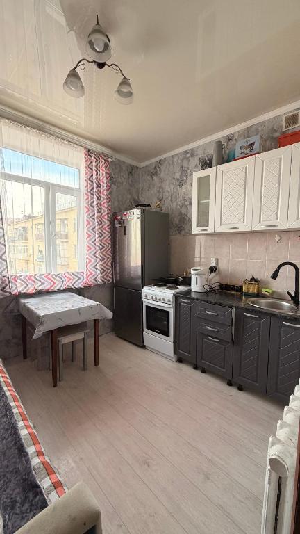 a kitchen with a refrigerator and a table in it at Квартира Алимжанова 16 Балхаш in Balqash