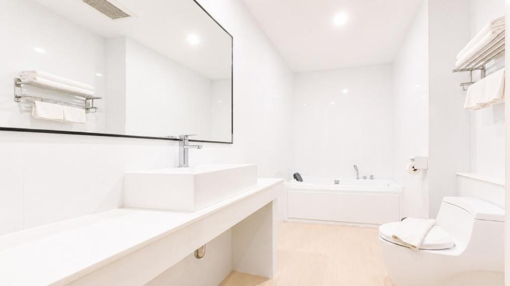 A bright white bathroom with a wide vanity, tub and toilet.
