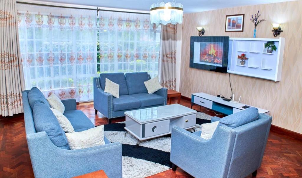 a living room with two blue chairs and a tv at Residence Next Door-5 in Nairobi