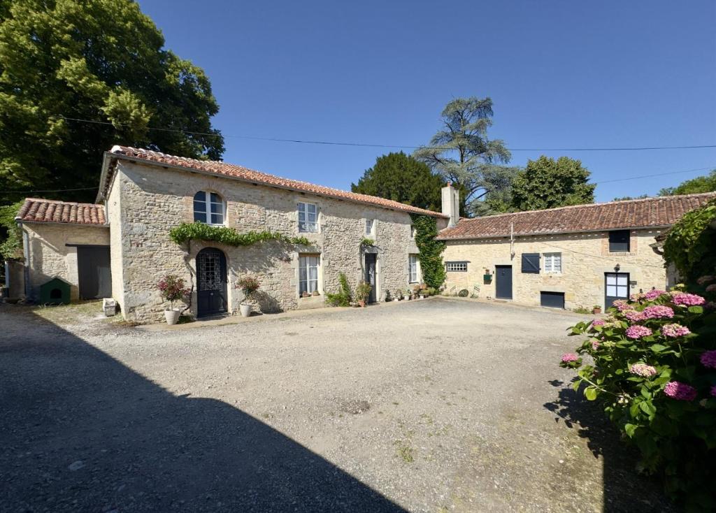 an old stone house with a driveway at La Maison de Lyon in Saint-Laurent-de-Céris