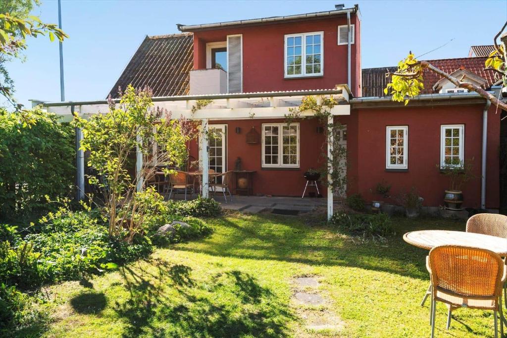 a red house with a table and chairs in the yard at 4263-Stege-Mollebrondstraede-13 in Stege