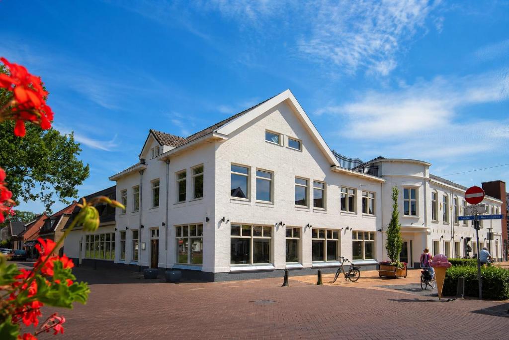 a large white building with windows on a street at Hotel de Zon in Oosterwolde