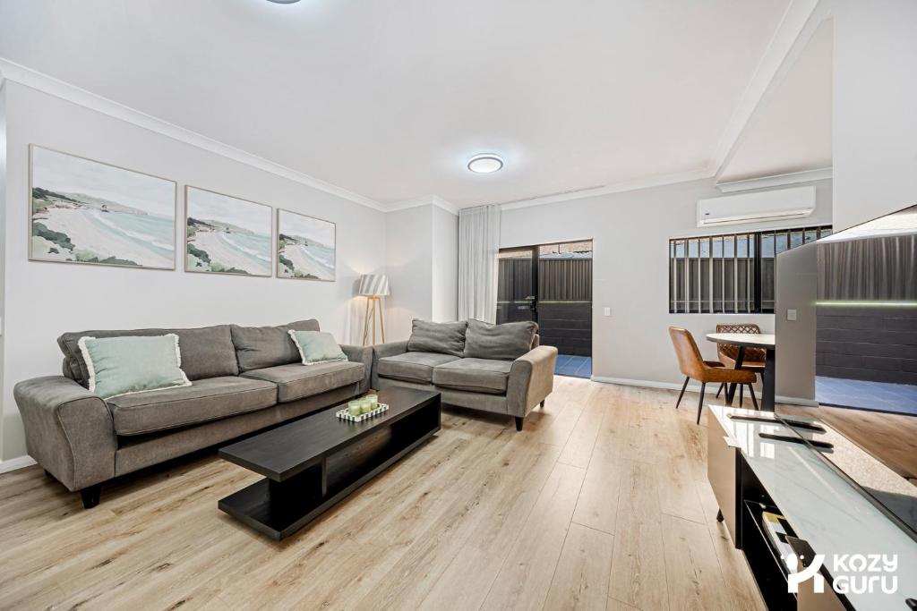 a living room with a couch and a table at KozyGuru | Penrith | Spacious Ground Floor Gem in Penrith
