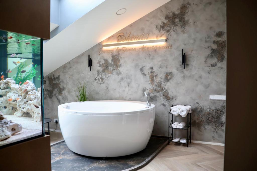 a bathroom with a large white bath tub in a room at Bohemia Jacuzzi & Sauna Apartment in Klaipėda
