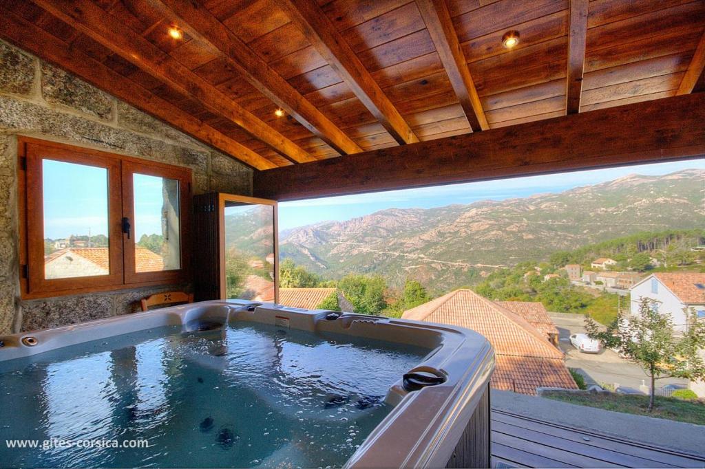 a large bath tub in a room with a large window at U san larenzu in Aullène