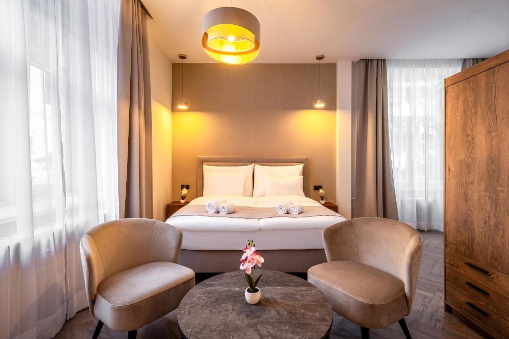 a bedroom with a bed with two chairs and a table at Evergreen Suites Budapest in Budapest