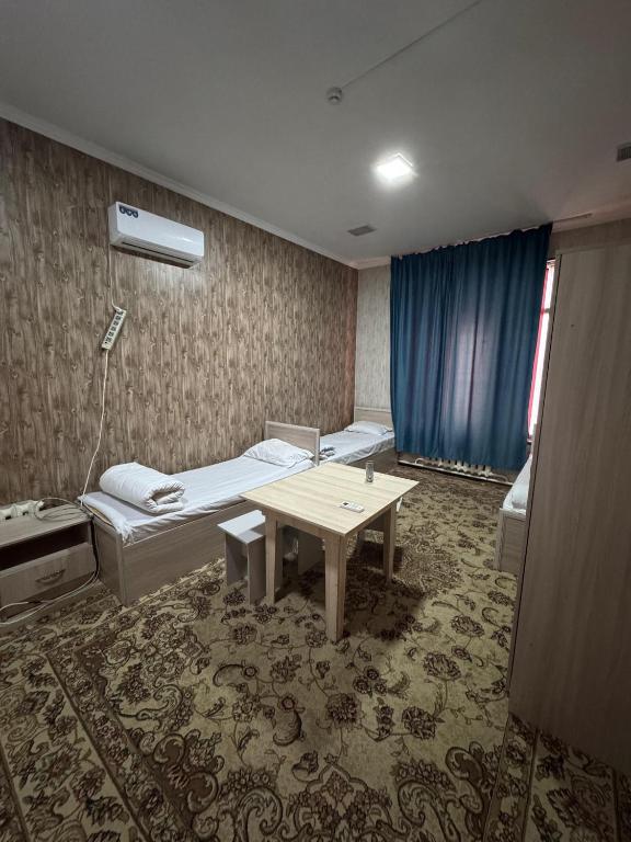 a room with two beds and a table in it at SaYAHAT TIMES in Türkistan