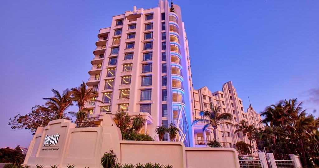 a tall building with palm trees in front of it at Suncoast Hotel & Towers in Durban