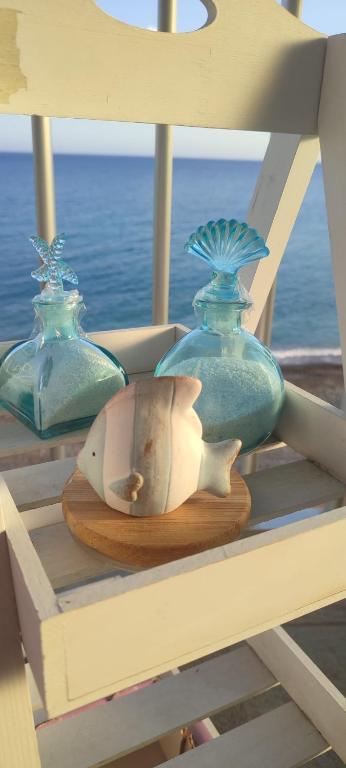 three blue glass vases sitting on a shelf next to the ocean at Appartamento ITACA - CITRA 08065-LT-0722 in Ventimiglia