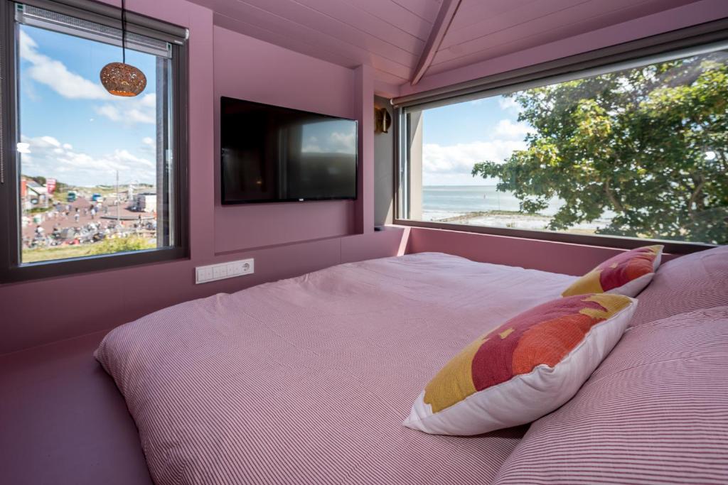 a bedroom with a large bed with a large window at Loods Logement in Oost-Vlieland
