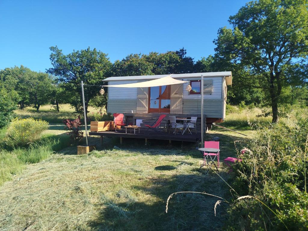 a tiny caravan with an umbrella and chairs in a field at Rials in Aleyrac