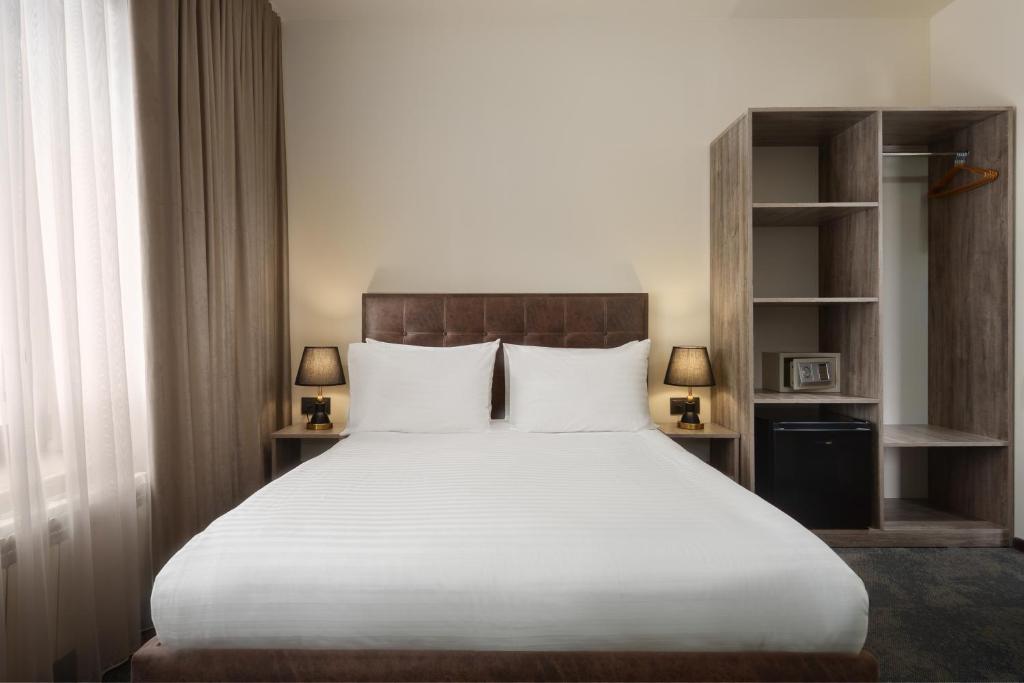 a bedroom with a large white bed with two lamps at Elysium Gallery Hotel in Yerevan
