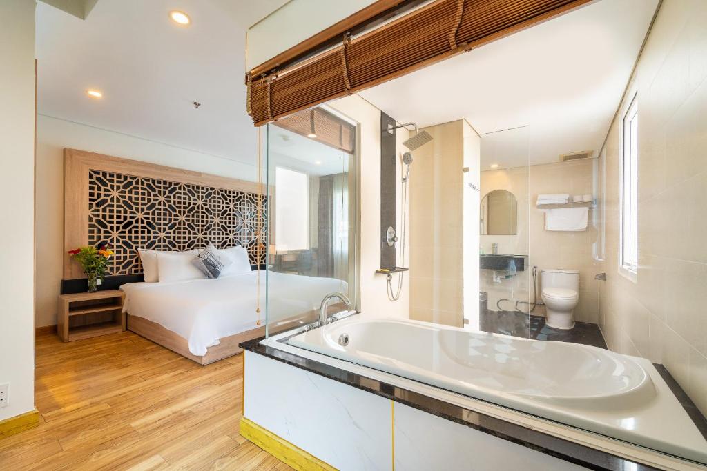 a bathroom with a tub and a bed in a room at Gemini Saigon LUXURY in Ho Chi Minh City