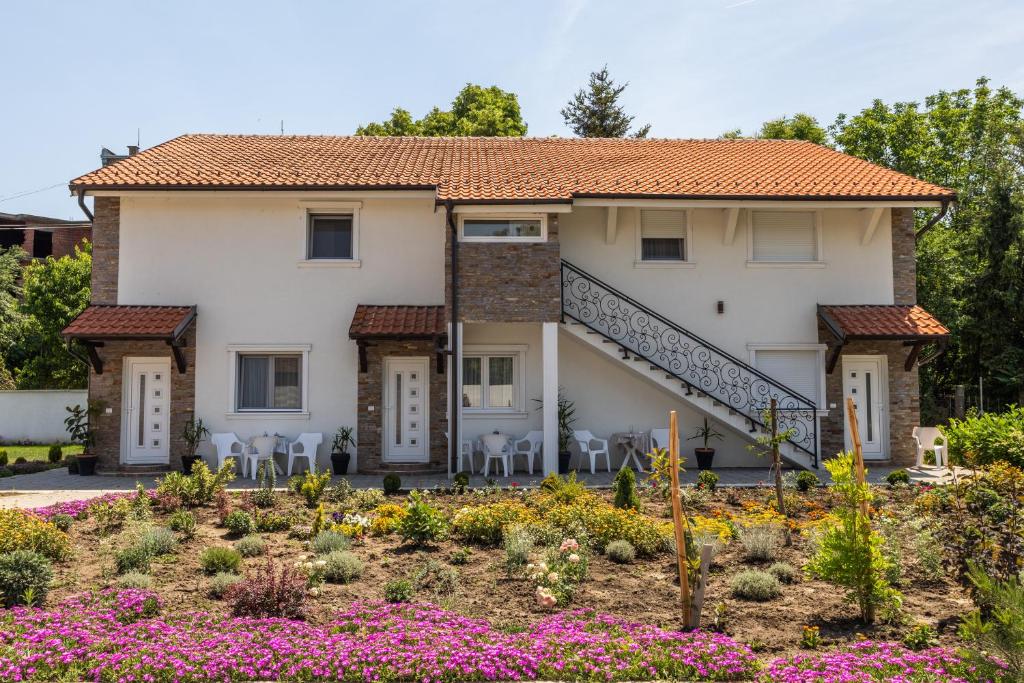 ein Haus mit Stühlen und Blumen in einem Garten in der Unterkunft Mariachi Surčin in Surčin