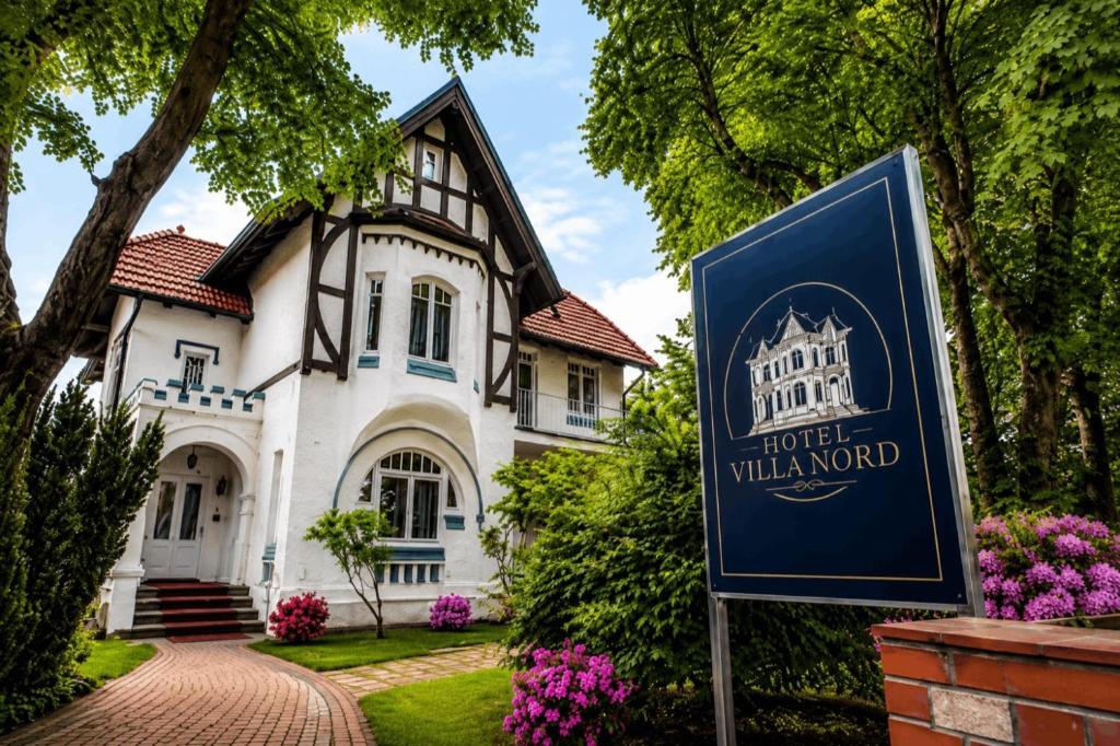 a sign in front of a house with a building at Hotel Villa Nord Hamburg-Airport in Hamburg