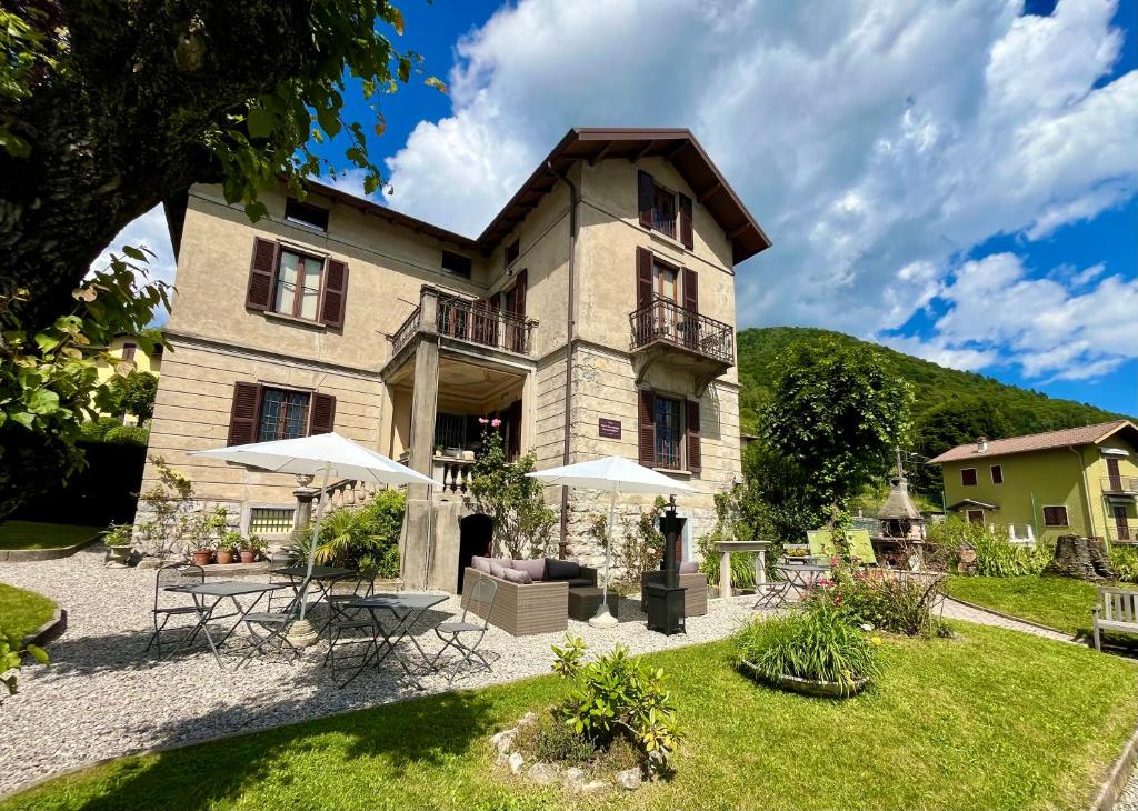a building with tables and umbrellas in front of it at Villa il Maiale Bianco Bed & Breakfast in San Fedele Intelvi