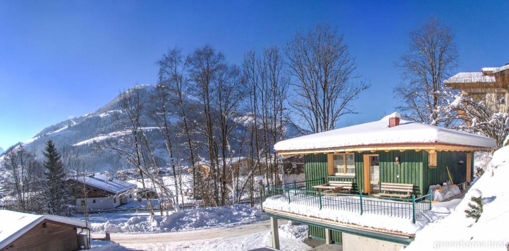 ein schneebedecktes Gebäude mit einem Berg im Hintergrund in der Unterkunft green Home - Sonniges Chalet in den Alpen in Kirchberg in Tirol