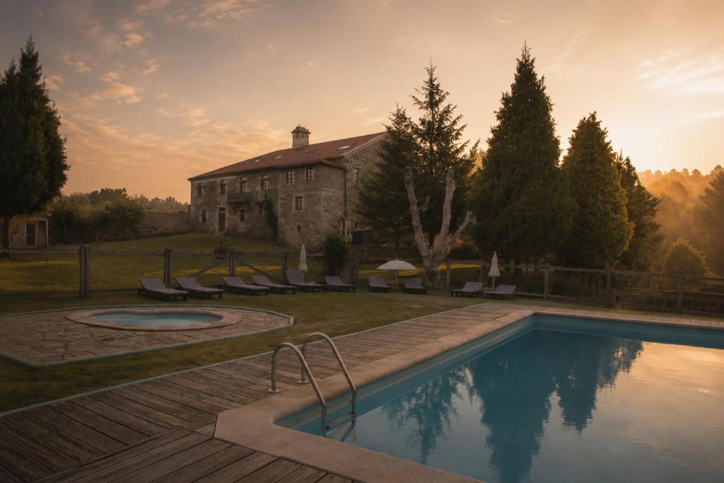 a house with a swimming pool in front of a building at Hotel Pazo Do Souto in Carballo
