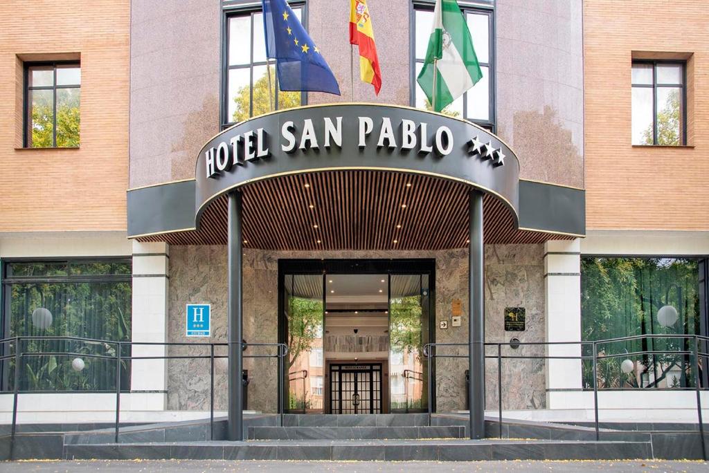 a hotel san pedro with two flags in front of it at Hotel San Pablo Sevilla in Seville