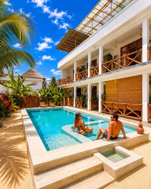 two people sitting in the swimming pool of a house at Olacoco by Olamanga in Jambiani