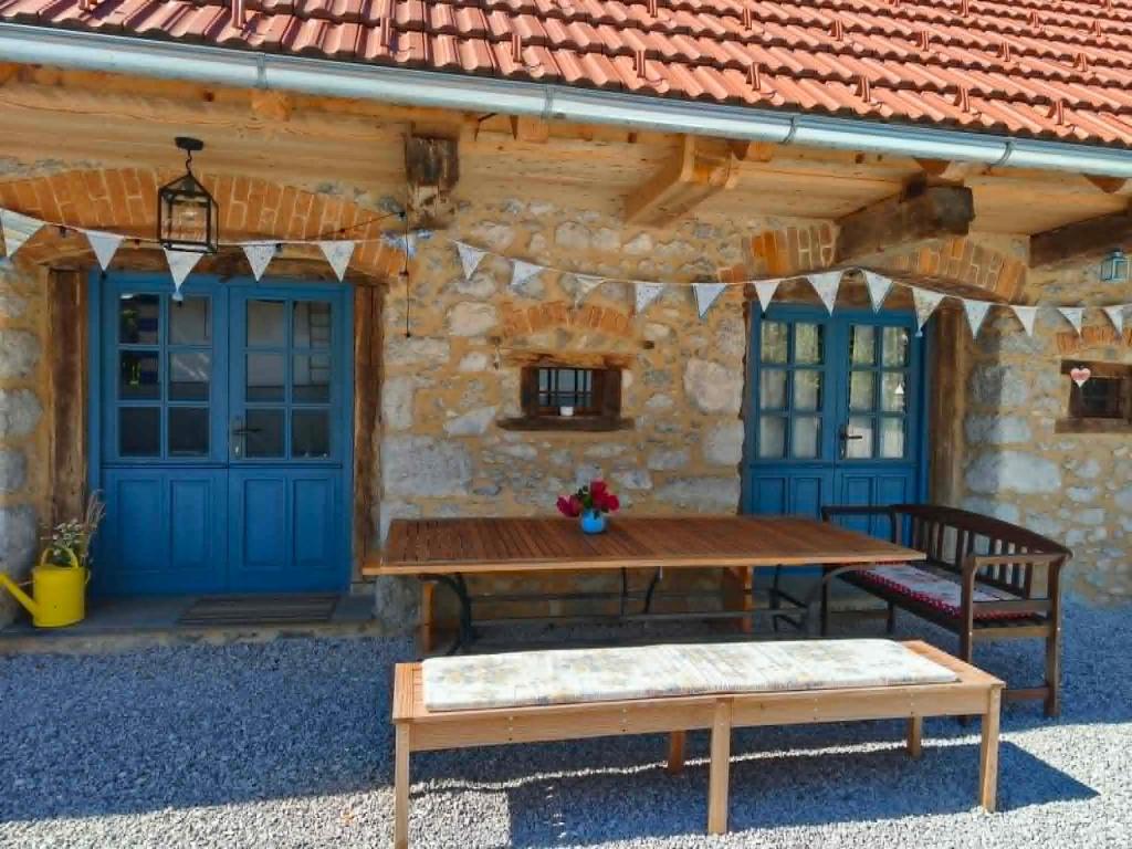 a wooden picnic table in front of a stone building at Štalca in Bušinja Vas