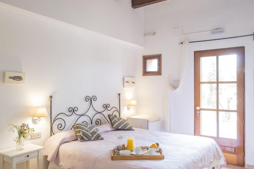 a white bedroom with a bed with a tray of food on it at Mas del Mar in Sant Pere Pescador