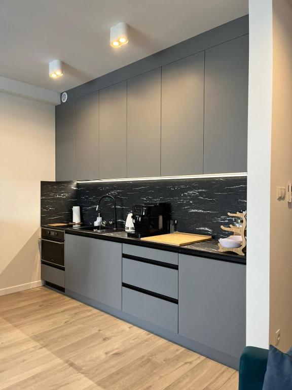 a kitchen with white cabinets and a black counter top at LUX Apartament Rogowo Pearl in Rogowo