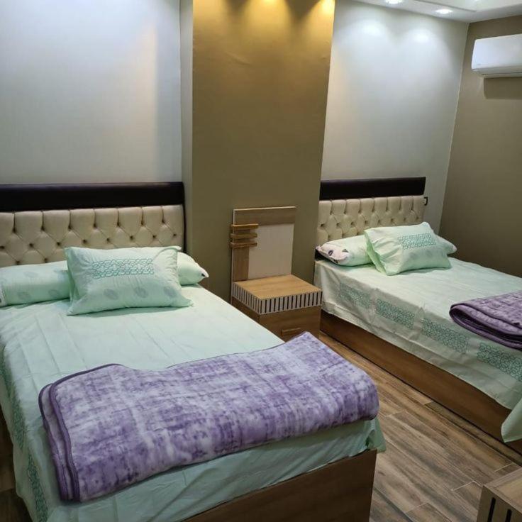 a bedroom with two beds with purple pillows at ابراج الصفوه الذهبيه 1 in Cairo