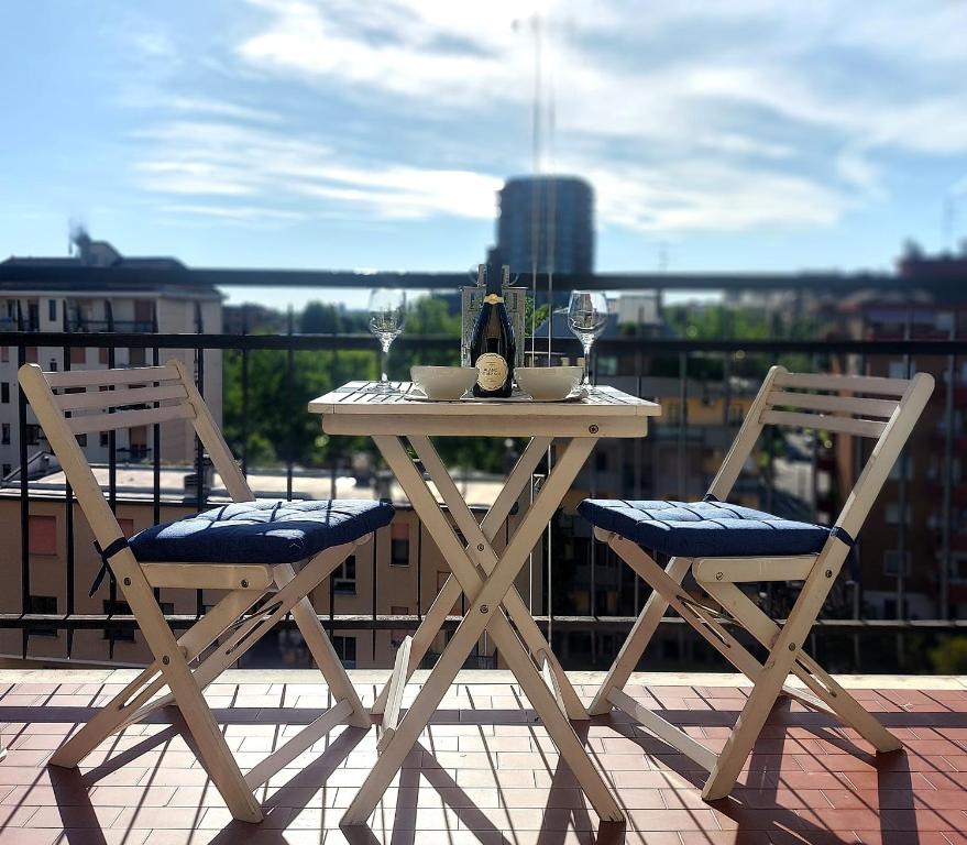 a table with two chairs and a bottle of wine on a balcony at Milan Top-Floor Flat City View 2 Balconies Workspace M5 in Milan