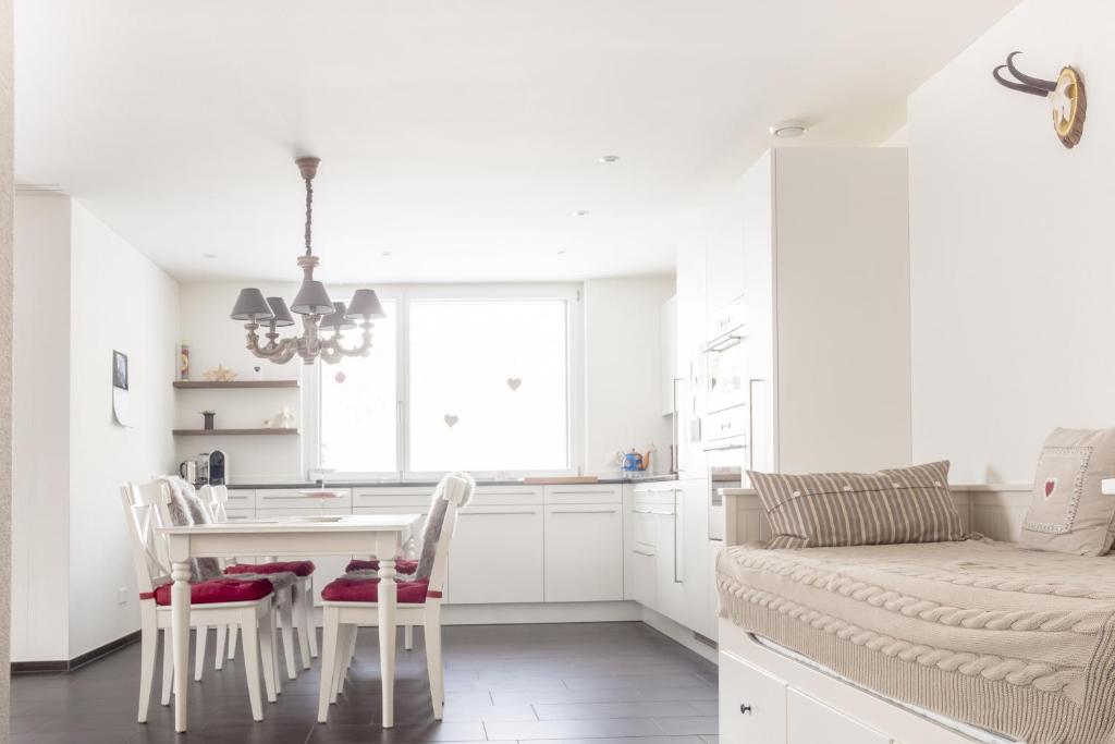 a white kitchen with a table and chairs and a couch at White Apartment in Andermatt