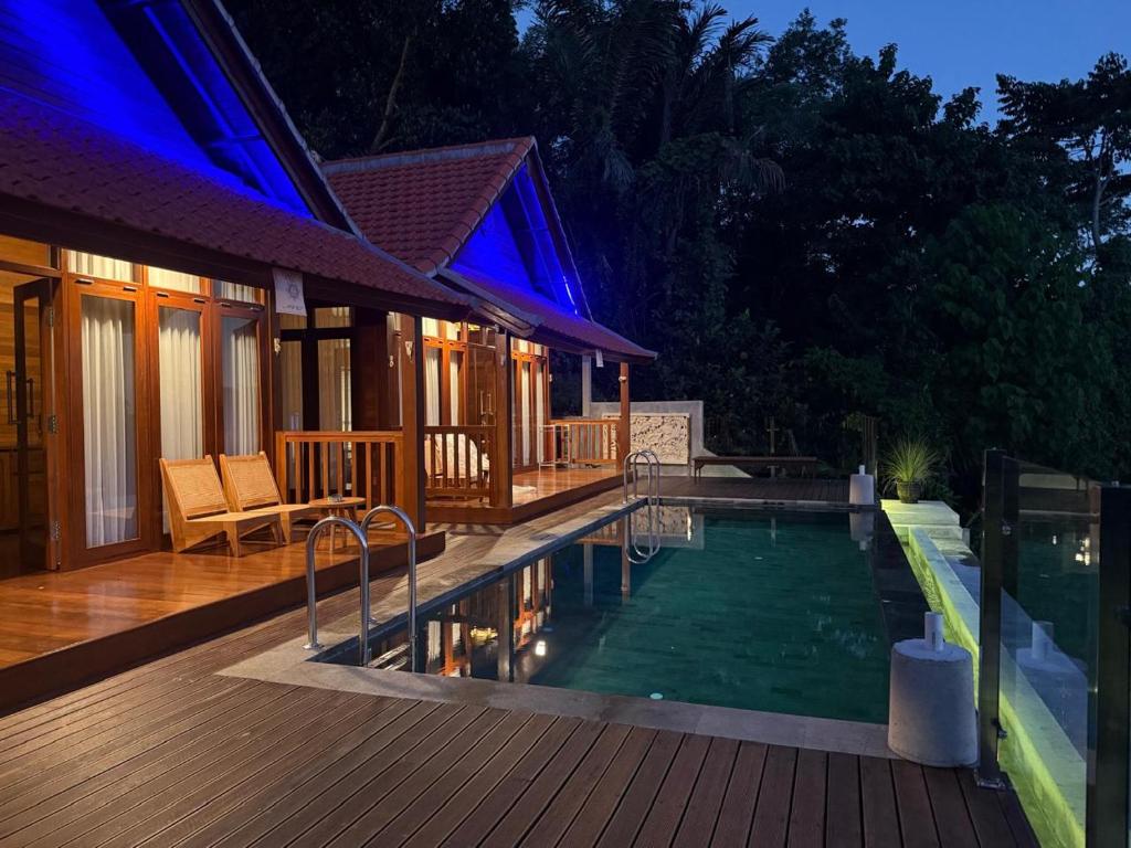 a house with a swimming pool on a wooden deck at Bukit Kembang Sari in Bugbug